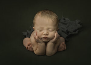 baby holding his face up with both hands in a froggy pose.