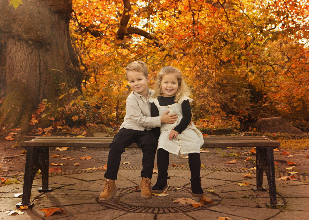 Brother and sister are sitting on a bench on a beautiful sunny, autumn morning. 