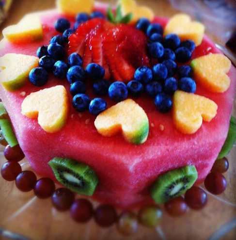 First birthday cake made of fruit. the base is from red watermelon and decorated with pineapple hearts, blueberries, kiwi, strawberry and grapes. 