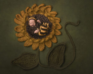 Smiling baby lying on crochet sunflower